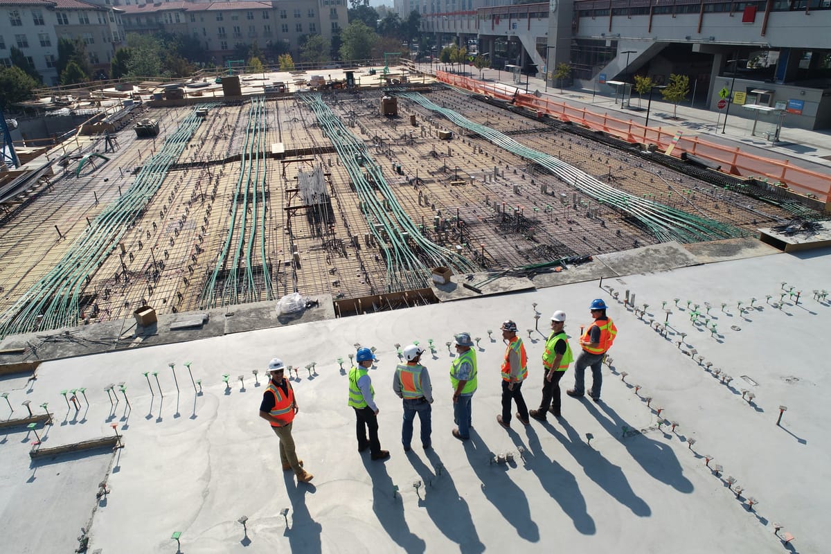 Top-down aerial view of a busy construction site with workers in view.