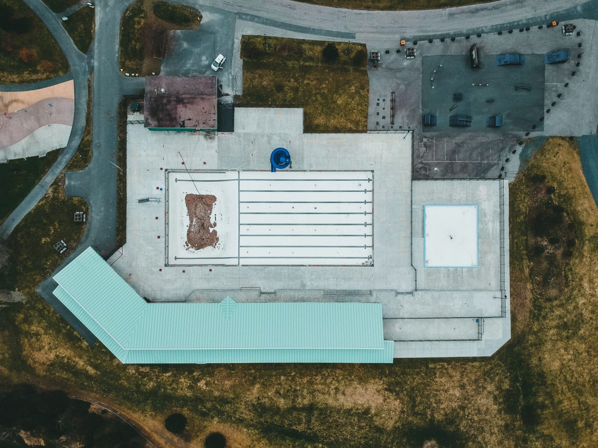 Aerial view of a large flat warehouse rooftop with industrial surroundings.