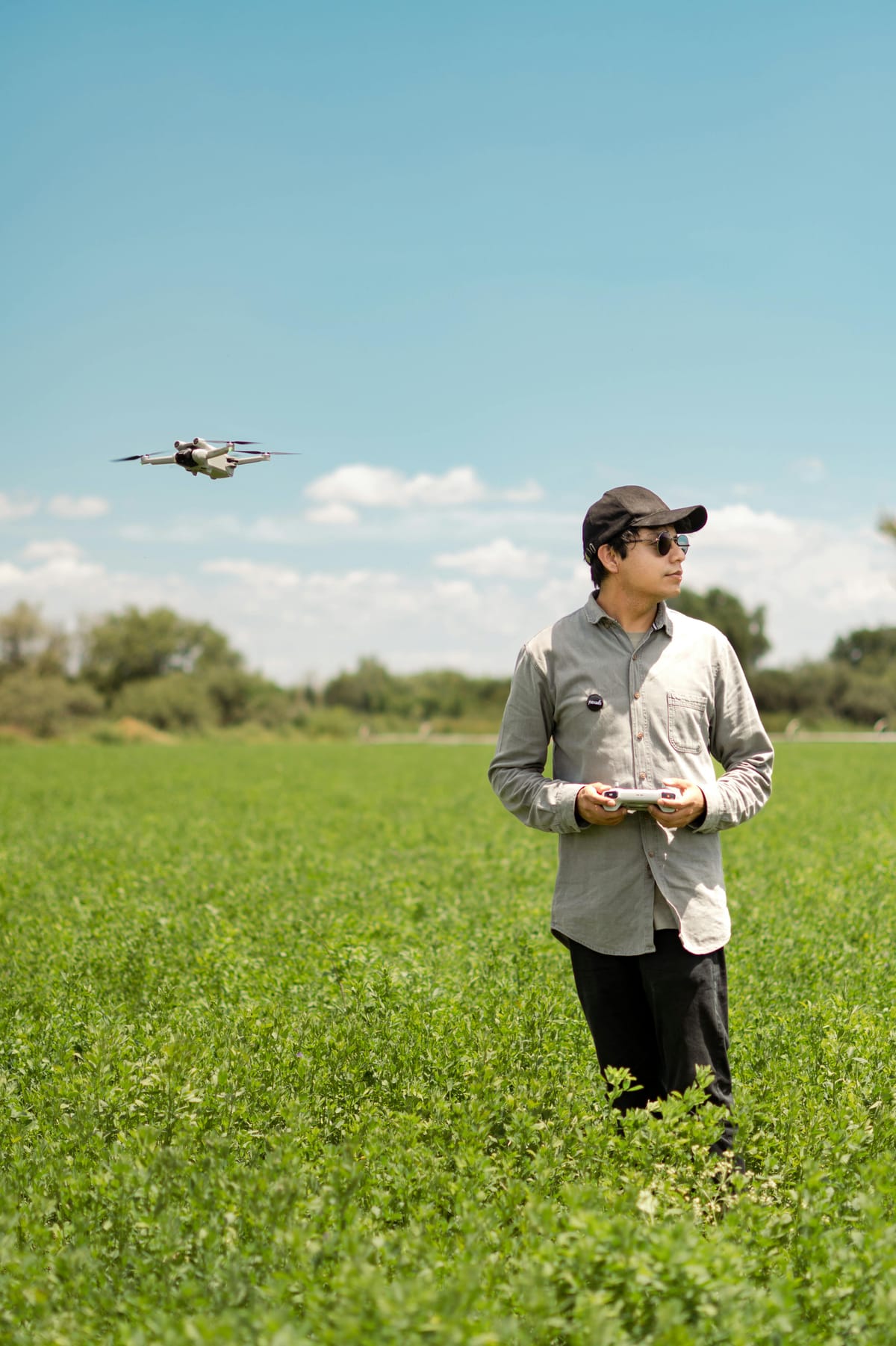 Drone operator in an open field conducting pre-flight checks with a drone at the ready.
