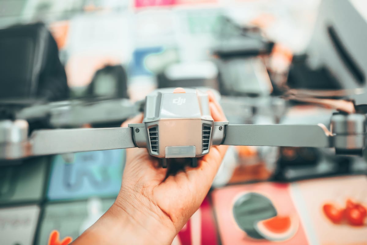 Man examining a drone closely indoors in daylight.