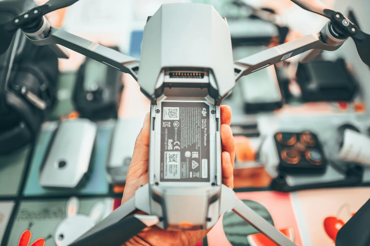 Close-up overhead view of an operator examining a drone camera and gimbal assembly during a detailed pre-flight inspection.