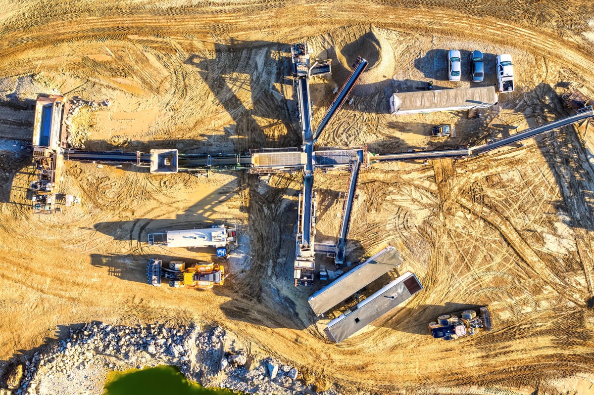 Aerial drone view of a remote industrial worksite with heavy equipment and open ground.