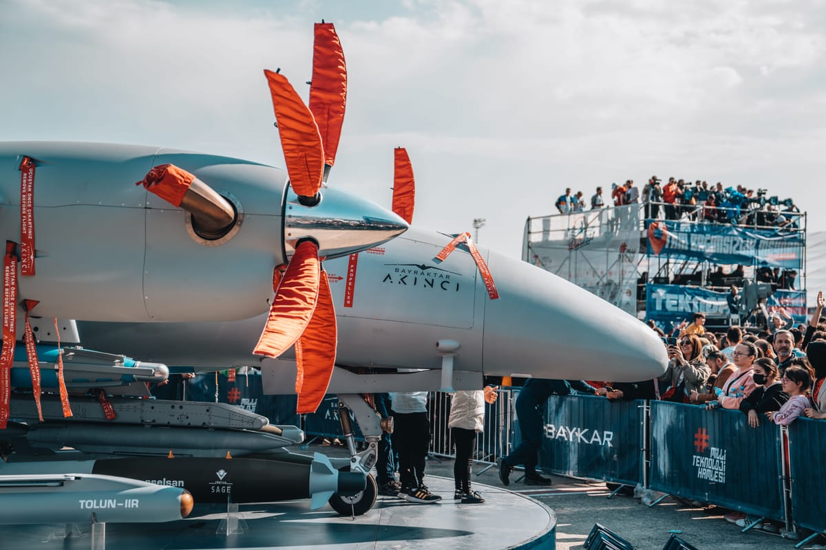 Military drone on display at an airshow with spectators nearby.