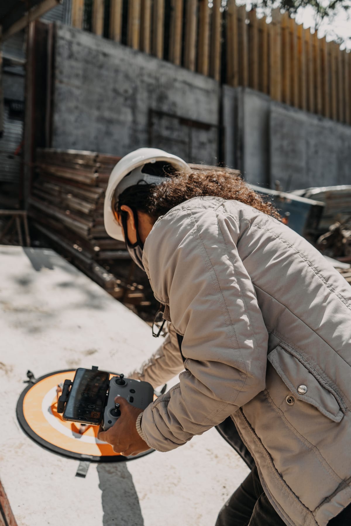 Drone pilot holding a controller at a worksite while preparing for a flight.