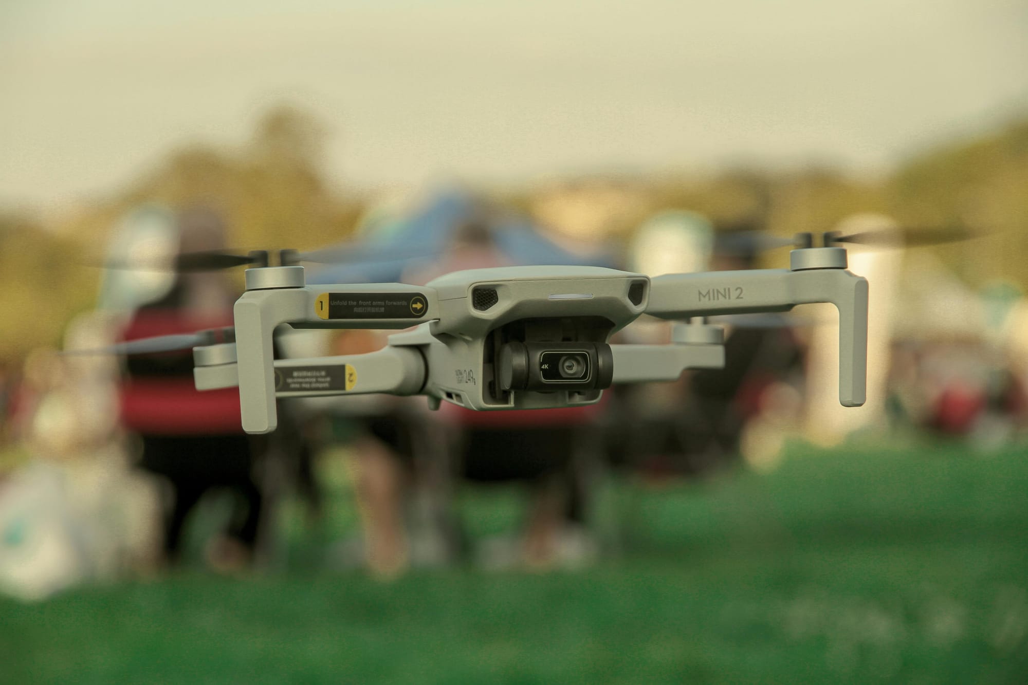 Drone in mid-flight against a pale cloudy sky, low-angle close-up.