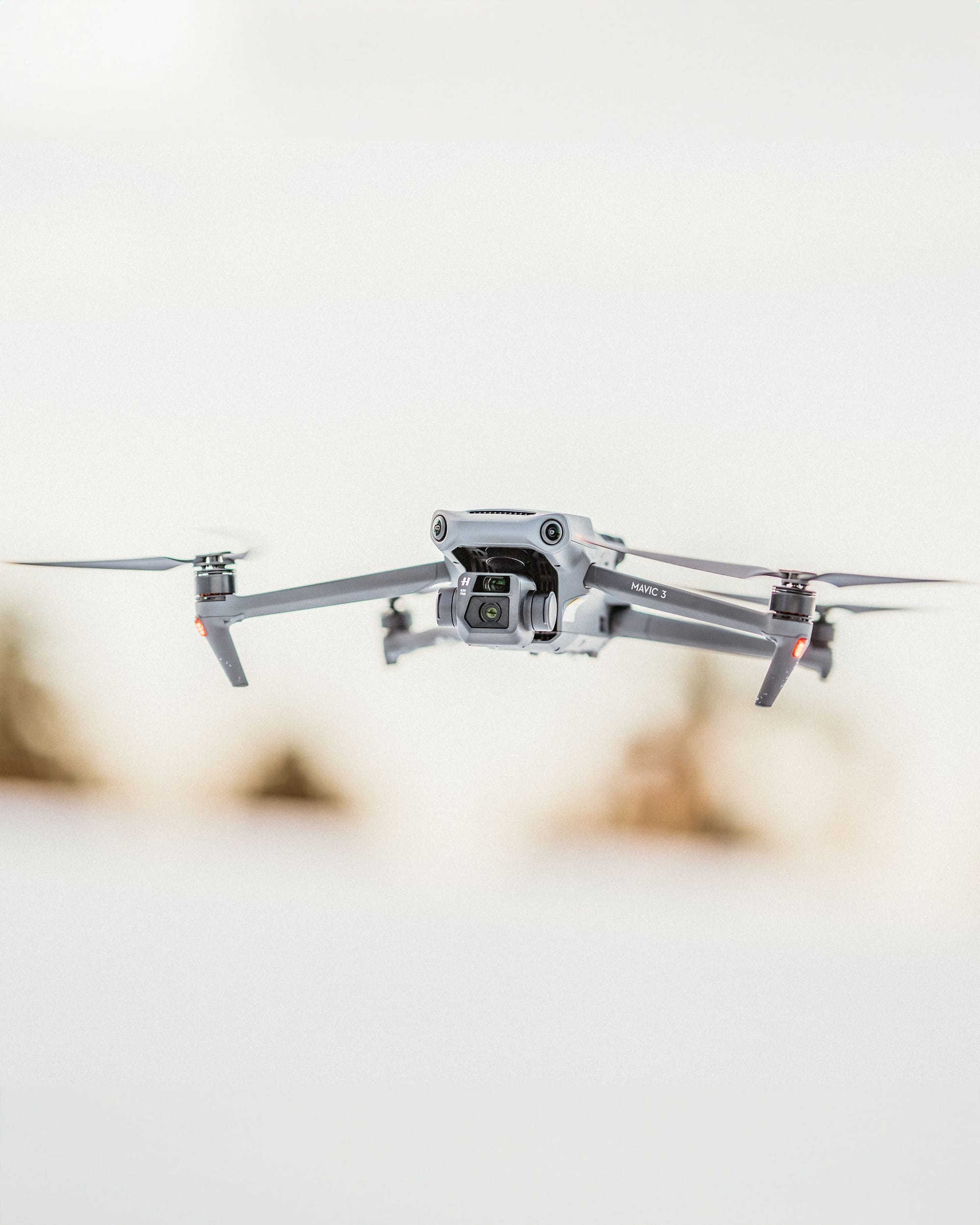 Close-up of a DJI Mini 2 drone in flight with blurred crowd in the background.