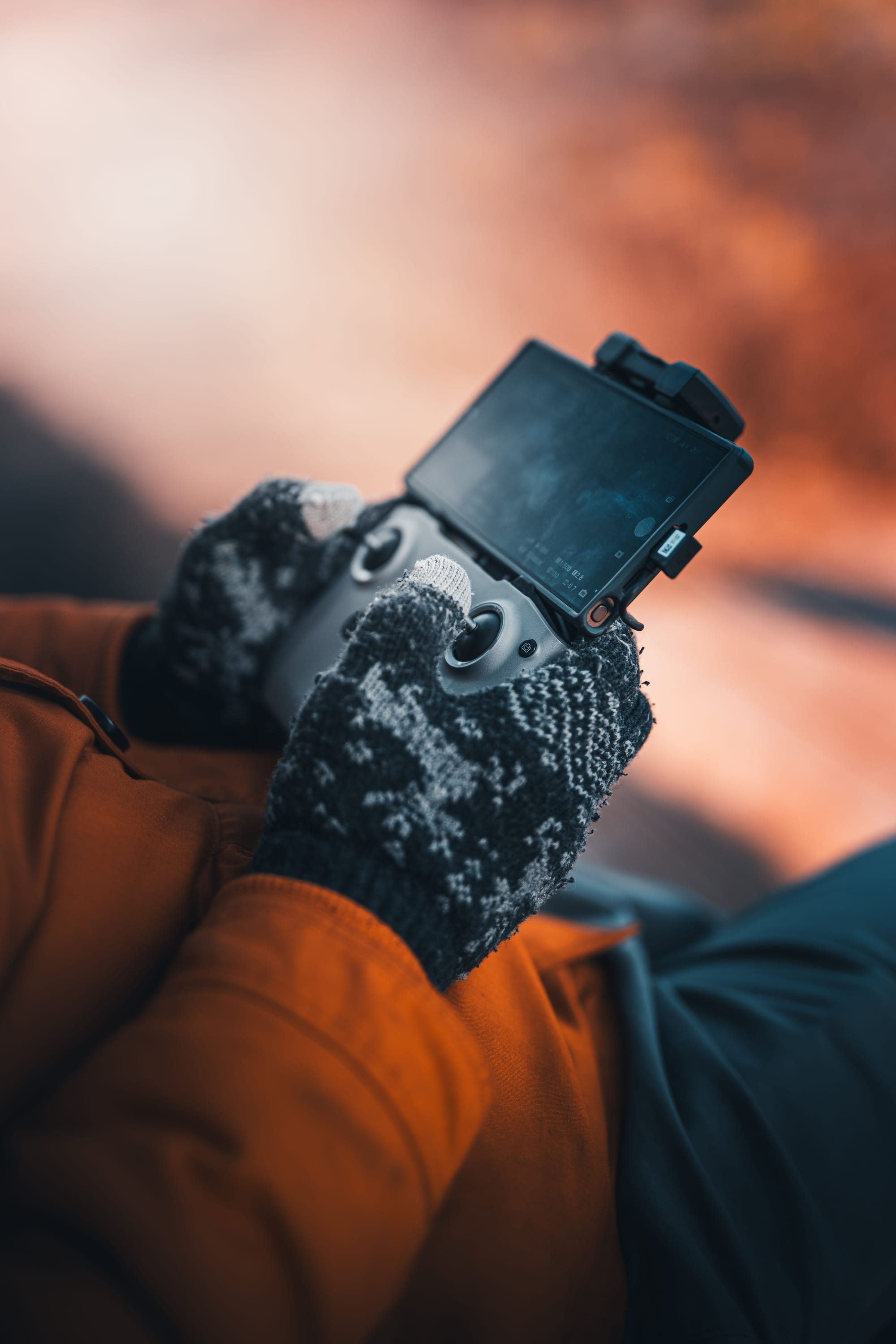 Close-up of gloved hands operating a drone remote controller outdoors.