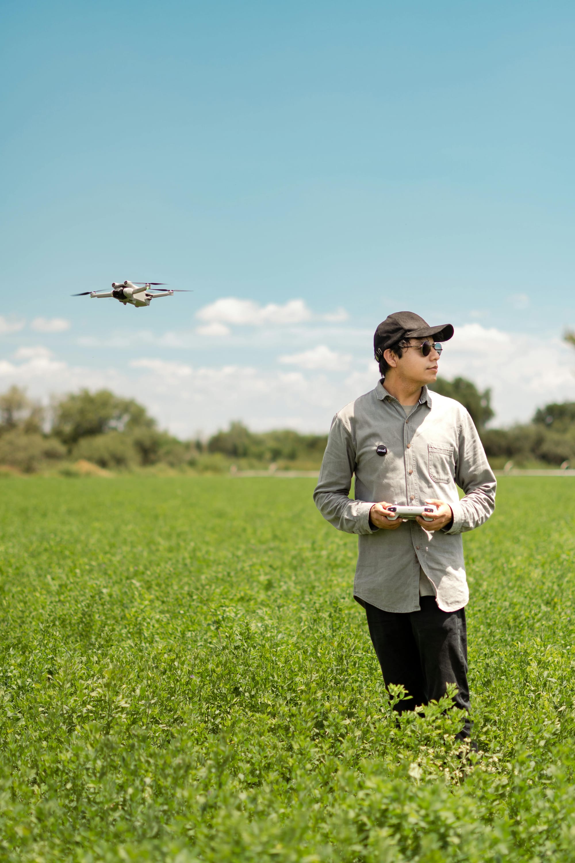 Drone operator in an open field conducting pre-flight checks with a drone at the ready.