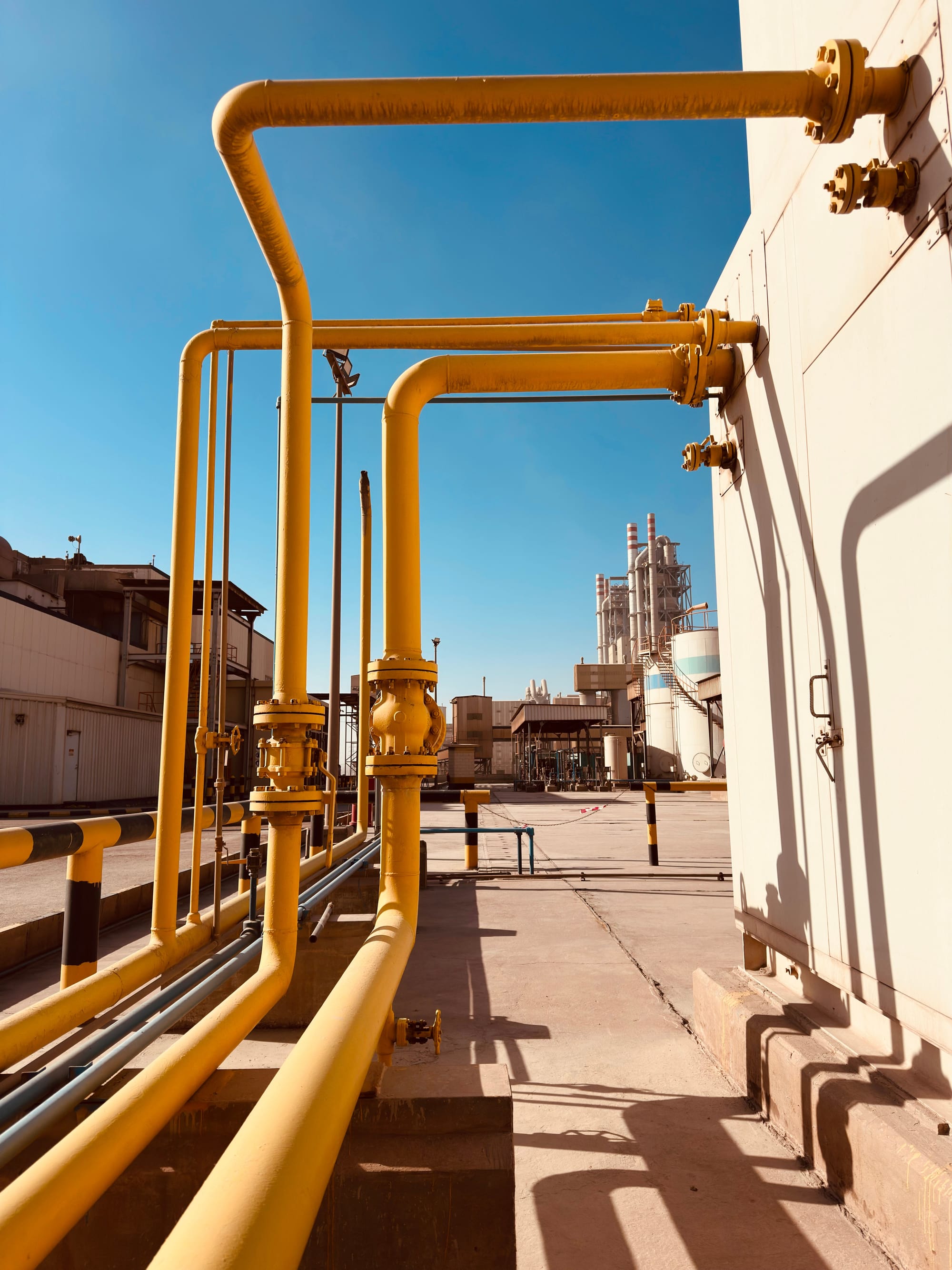 Yellow industrial gas pipeline running through an arid rural landscape under clear sky.