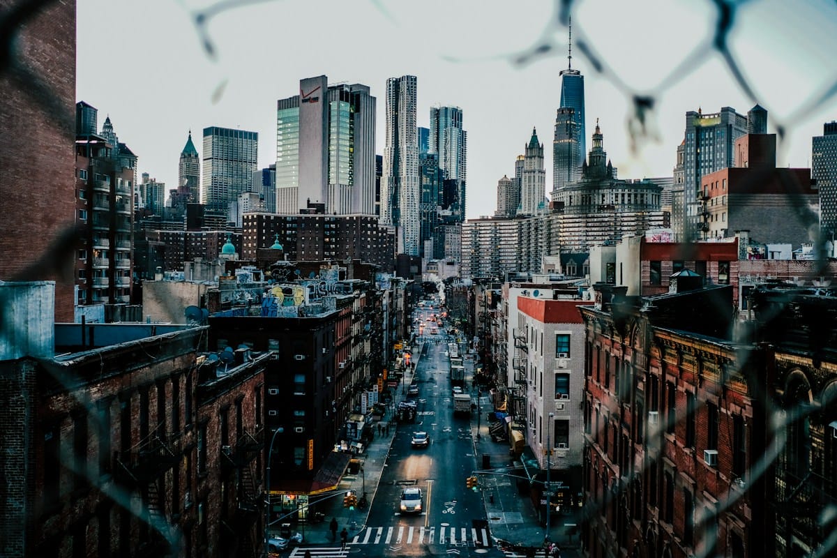 A city street lined with buildings leading toward a high-rise skyline.